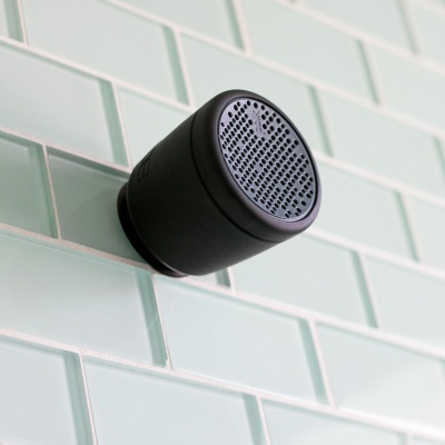 Coluna sonora preta montada em parede de azulejos verdes claros