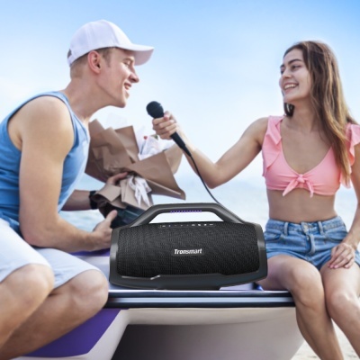 Coluna portátil Bluetooth preta Tronsmart sobre prancha de surf ao ar livre junto ao mar.