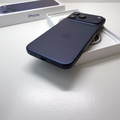 Smartphone iPhone azul escuro com três câmeras na parte traseira junto à caixa aberta