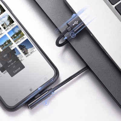 Cabo USB preto trançado entre portátil cinzento e smartphone mostrando galeria de fotos