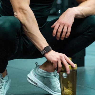 Pessoa com relógio inteligente e garrafa Blender Bottle num ginásio