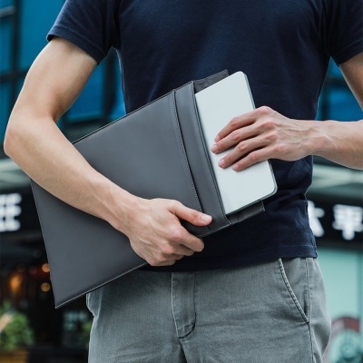 Mala fino preta em pele a segurar um tablet branco por uma pessoa ao ar livre