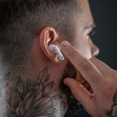Auricular branco sem fios no ouvido de homem com tatuagem e cabelo curto