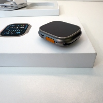 Relógio inteligente cinza com botão laranja numa caixa branca