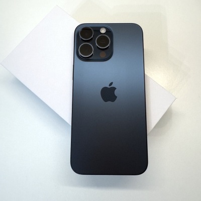 Smartphone preto Apple com três câmeras traseiras sobre caixa branca e fundo branco