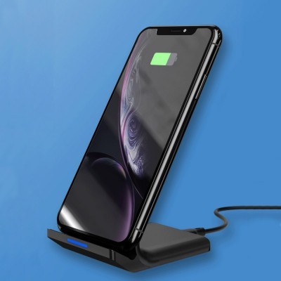 Smartphone preto a carregar num suporte de carregamento sem fios preto sobre fundo azul