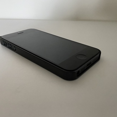 Smartphone preto com ecrã desligado colocado numa superfície branca
