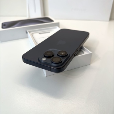Smartphone preto com três câmaras sobre caixa branca aberta em superfície branca