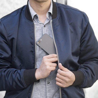 Homem de bomber jacket azul escura a segurar smartphone cinzento