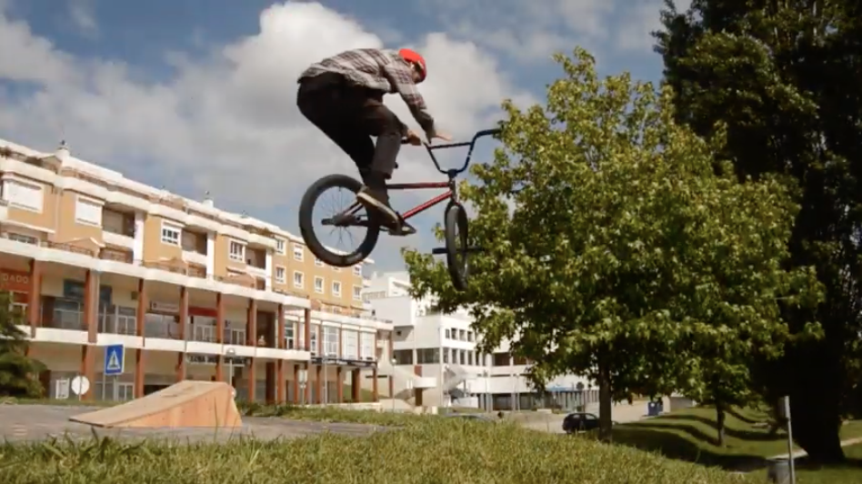 Ciclista com bicicleta BMX a fazer manobra aérea em ambiente urbano