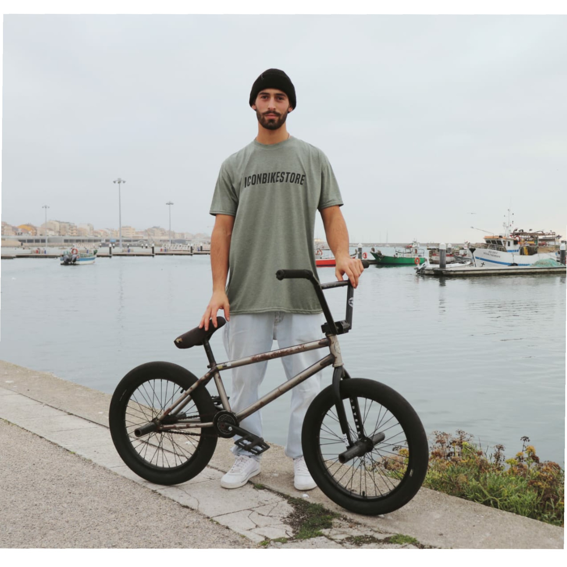 Homem com bicicleta BMX ao lado de um porto com barcos