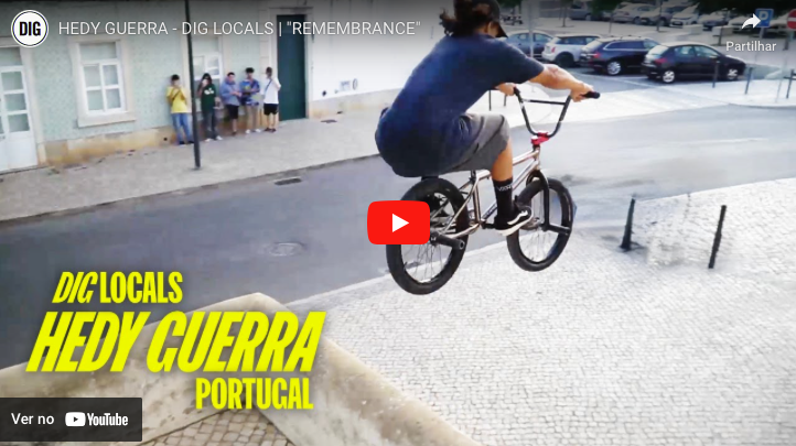 Jovem em bicicleta BMX a saltar na calçada portuguesa com pessoas ao fundo