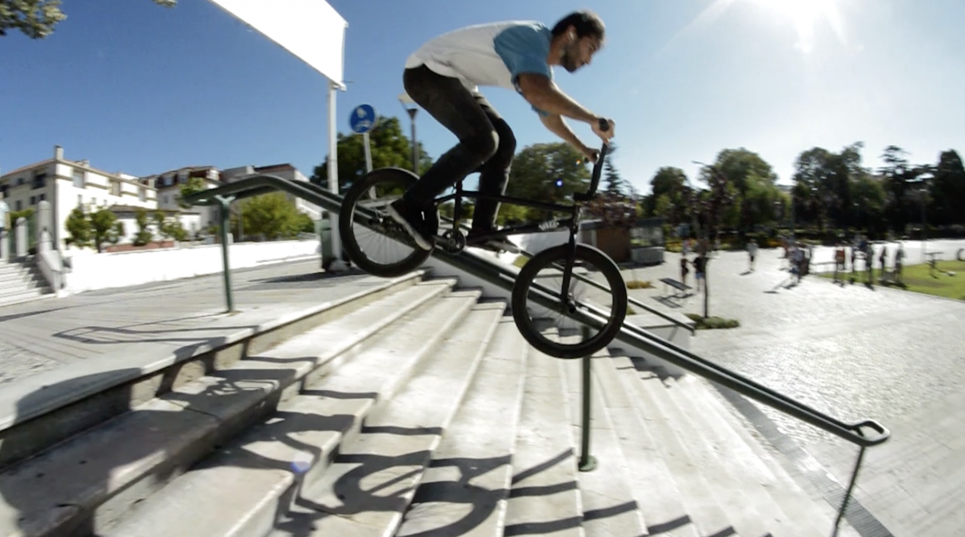 Homem a descer corrimão de escadas com bicicleta BMX preta ao ar livre