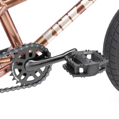 Detalhe da pedaleira e roda traseira de bicicleta com quadro metálico bronze e branco