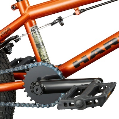 Quadro de bicicleta laranja com pedal e corrente em detalhe