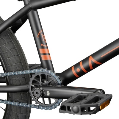 Detalhe de bicicleta BMX preta com pedais e correntes