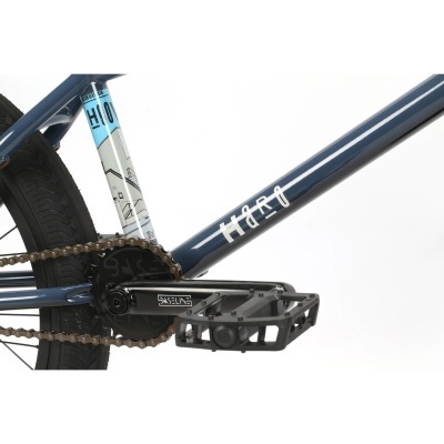 Parte da bicicleta azul escura com detalhes, pedais pretos e corrente dourada