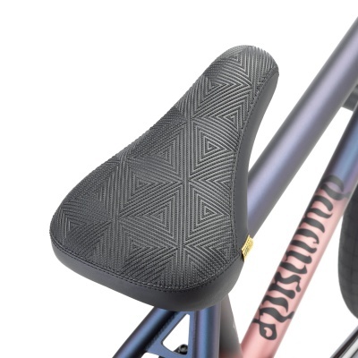 Selim de bicicleta preto com padrão triangular e estrutura azul e rosa com texto MINIVELO