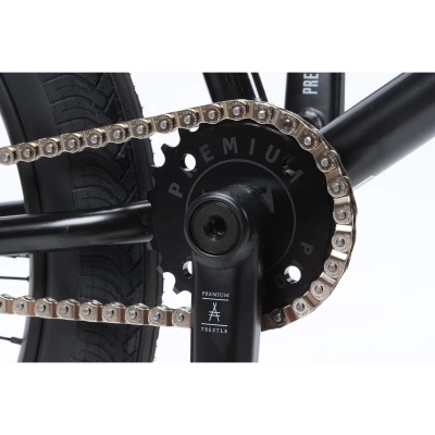 Detalhe da roda e corrente de bicicleta preta com texto PREMUIM e PREMIUM TREASTLE