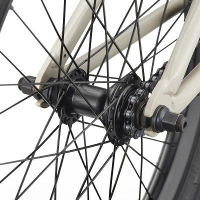 Cubo traseiro e raios pretos de roda de bicicleta com quadro bege e corrente metálica.