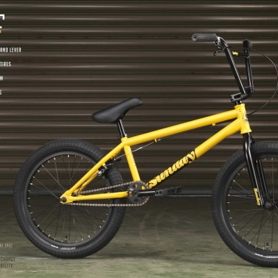 Bicicleta BMX amarela com pneus pretos e fundo de porta metálica preta