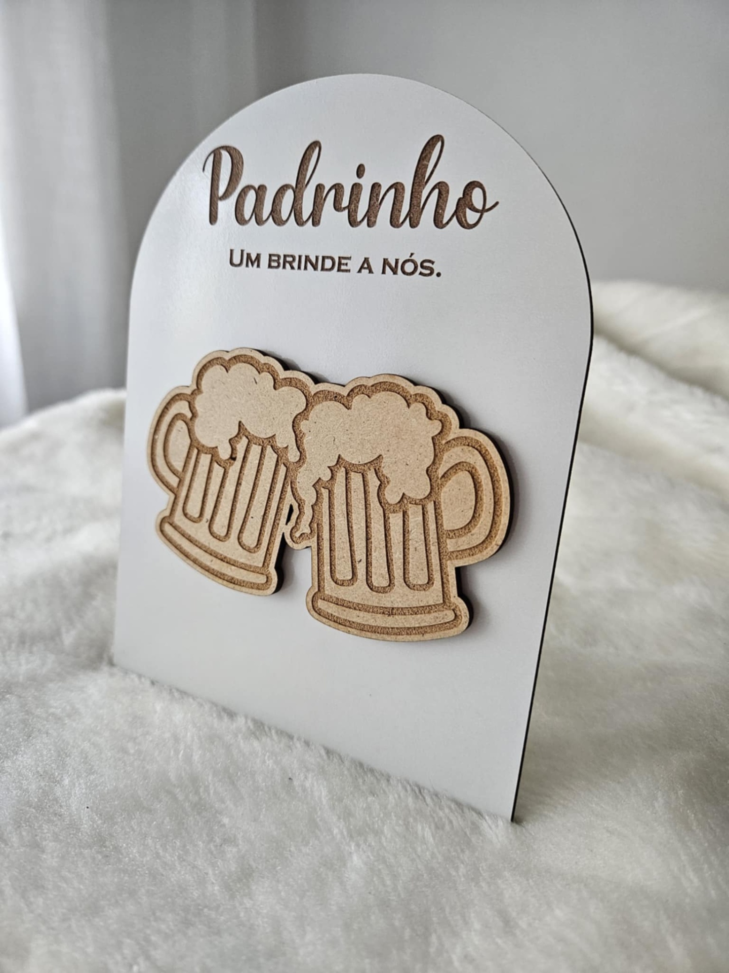 Cartão branco com texto Padrinho UM BRINDE A NÓS. e duas canecas de cerveja em madeira