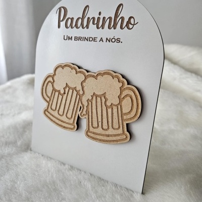 Cartão branco com texto Padrinho UM BRINDE A NÓS. e duas canecas de cerveja em madeira