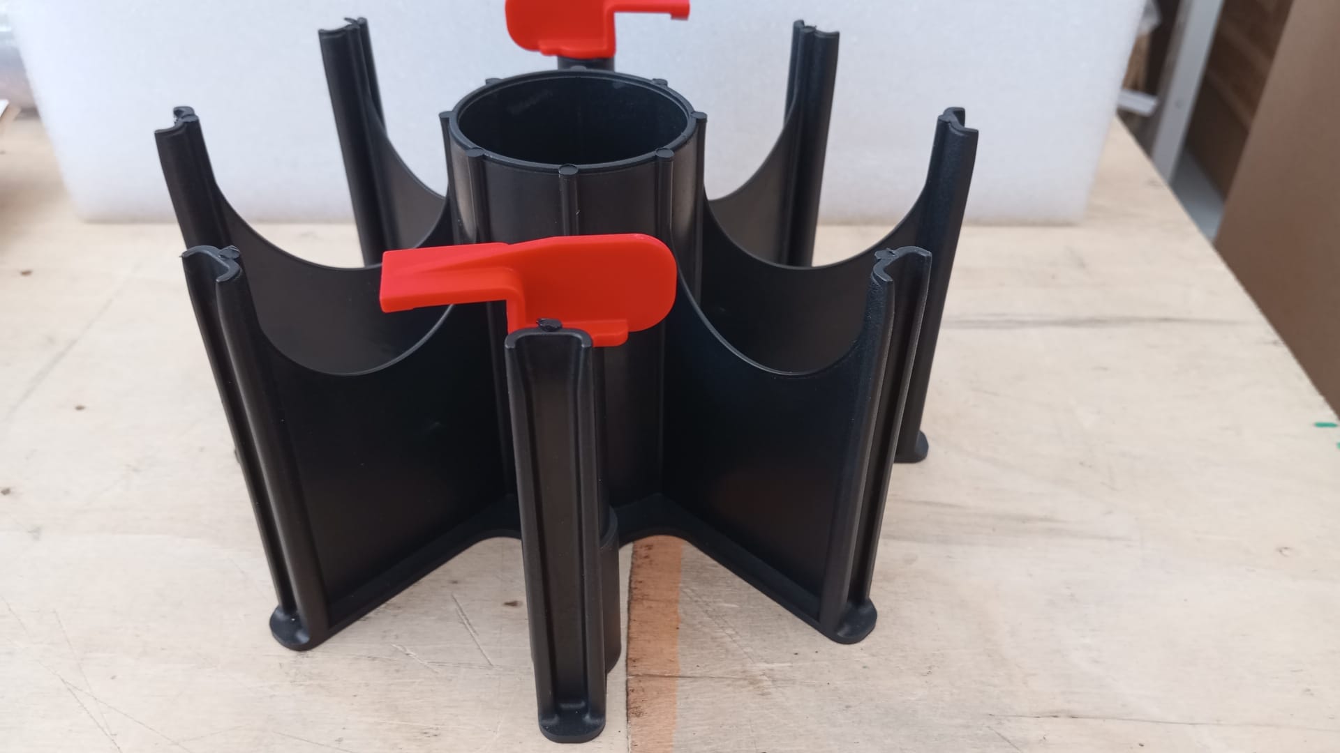 Suporte preto com divisórias e abas vermelhas sobre mesa de madeira