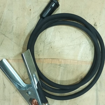 Cabo preto com pinça metálica e peça de cobre sobre superfície de madeira