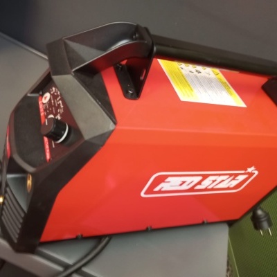 Máquina de soldar vermelha e preta STEL com cabo preto numa superfície cinzenta