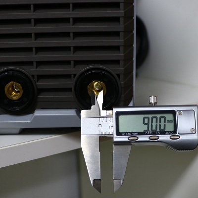 Paquímetro digital medindo peça metálica dourada numa caixa cinzenta