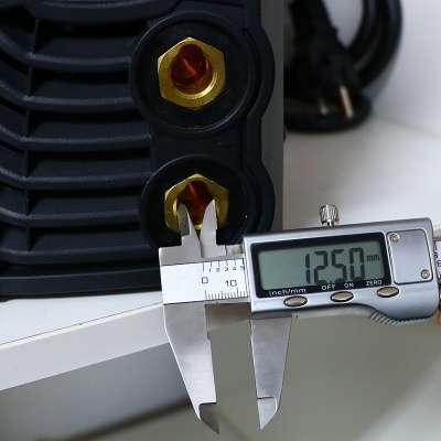 Medição com paquímetro digital numa peça preta com ligações douradas