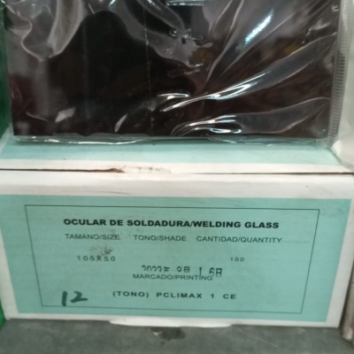 Vidro de soldadura preto embalado, com caixa etiquetada, num ambiente de armazém