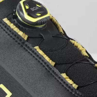 Detalhe de sapatilha desportiva preta com sistema de ajuste BOA e detalhes em amarelo