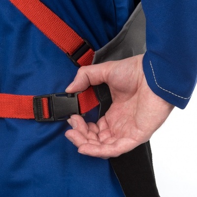 Mão a ajustar fivela preta numa correia vermelha sobre tecido azul