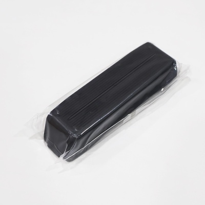 Peça preta riscada embalada em plástico transparente sobre superfície branca