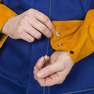 Detalhe de casaco azul com mangas amarelas e botões metálicos nas punhos