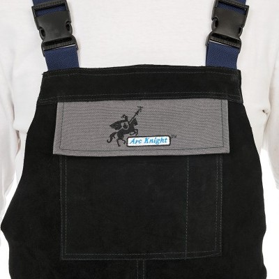 Jardineira preta com bolso cinzento e etiqueta 'Arc Knight', usada sobre t-shirt branca de mangas compridas.