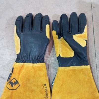 Luvas de proteção toque preto e camurça amarela com punho longo sobre superfície clara