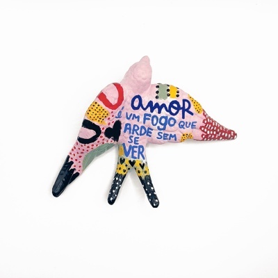 Escultura colorida em forma de pássaro com texto em português