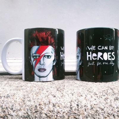 Canecas pretas com imagem de David Bowie e texto WE CAN BE HEROES