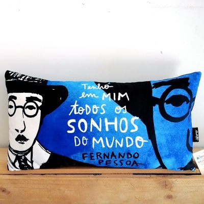 Almofada decorativa azul e preta com texto em branco e rosto ilustrado