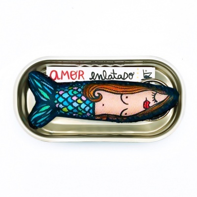 Lata metálica aberta com almofada de sereia bordada e papel com texto