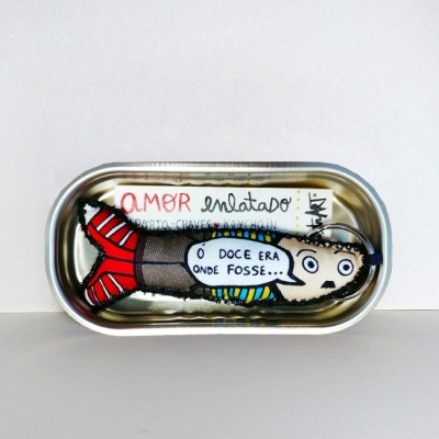 Lata metálica com boneca em tecido colorido dentro e textos escritos