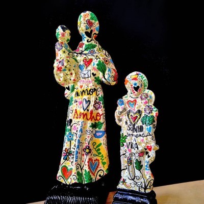 Duas estatuetas coloridas pintadas à mão com corações e flores em fundo preto