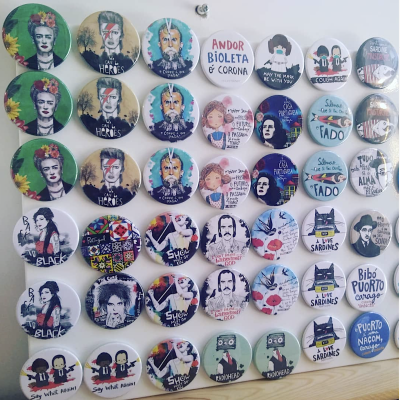 Botões redondos com diferentes ilustrações e textos em português dispostos sobre superfície de madeira.