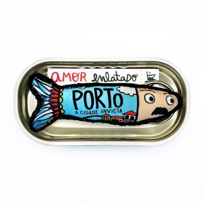 Almofada em forma de sardinha dentro de lata metálica dourada