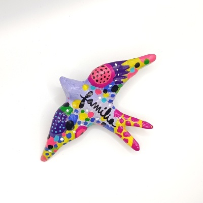 Peça decorativa colorida em forma de pássaro com a palavra 'familia'