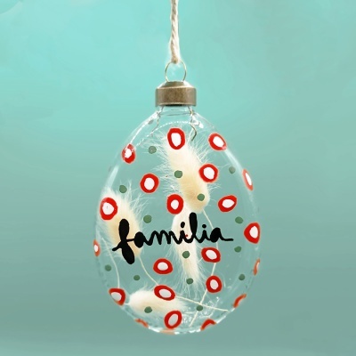 Ornamento oval em vidro transparente com decoração vermelha e branca e palavra familia