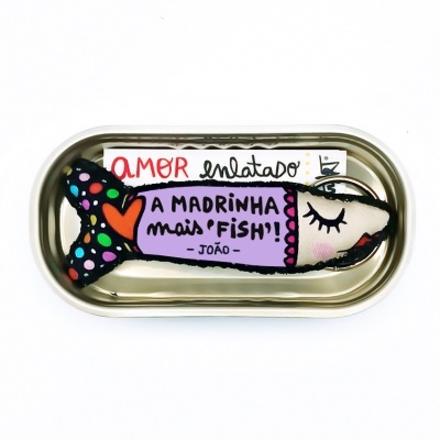 Lata metálica brilhante com peixe de tecido colorido e texto em português
